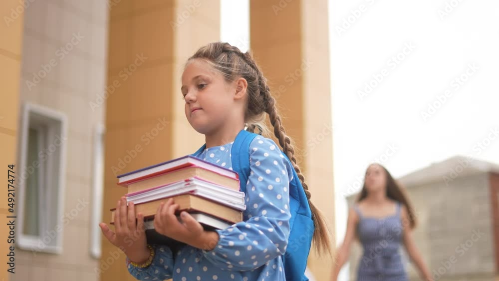 back to school. schoolgirl carries textbooks books go to school behind with a backpack holding hands. kid education school concept. first grader going to school group of kids. child student walk back to school. schoolgirl carries textbooks books go to school behind with a backpack holding hands. kid education school concept. first grader going to school group of kids. child student walk