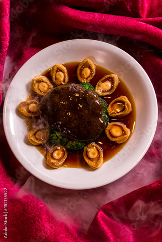 braised vegetable broccoli with mushroom and premium abalone in soy stock sauce cinese banquet menu on red cloth background photo