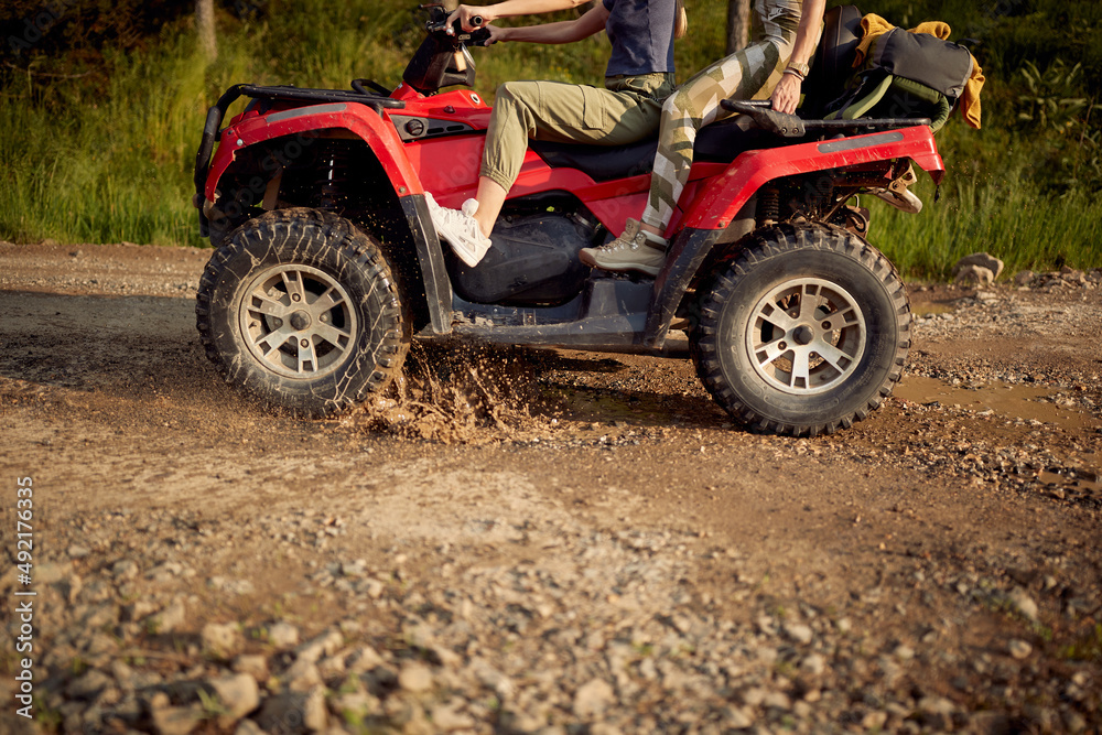 Young girls enjoying a quad ride on a muddy road in the nature. Riding, nature, friendship, together