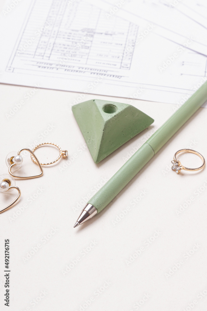 Fototapeta premium Green pen, jewelry and drawings on white background. Women's workplace. Female engineer, designer or architect