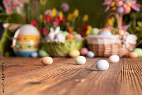 Easter time. Easter decorations on the rustic wooden table. Easter bunny, easter eggs in basket. Bouquets of spring flowers. 