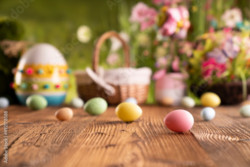 Easter time. Easter decorations on the rustic wooden table. Easter bunny, easter eggs in basket. Bouquets of spring flowers. 