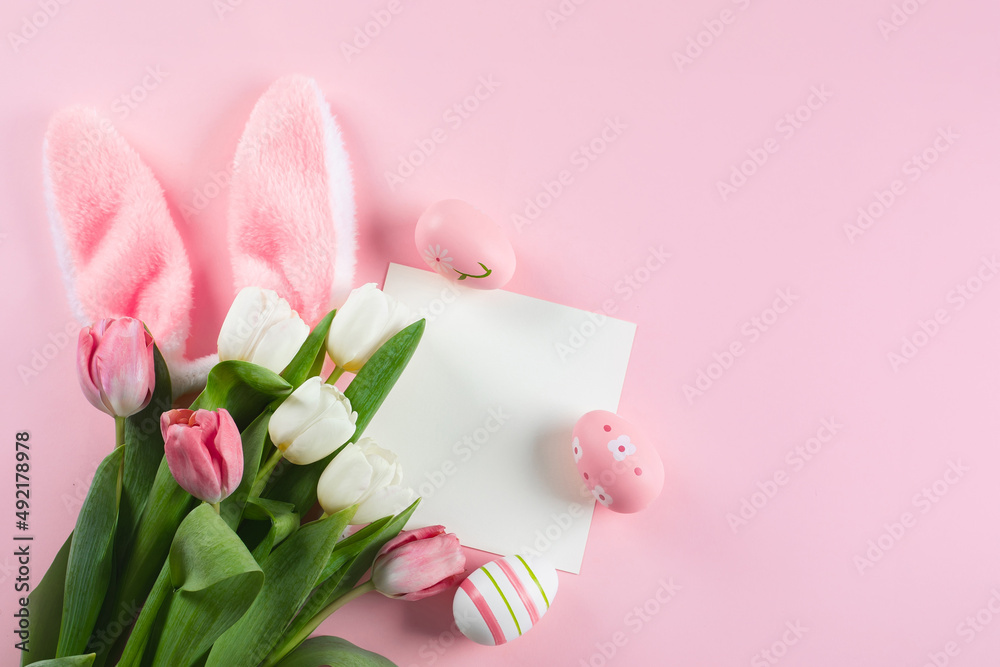 Easter background with easter eggs, fluffy bunny ears, spring tulips and empty card for text. Mockup.