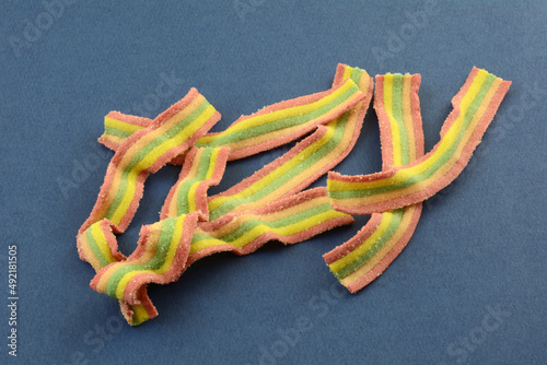 Принти на полотні Sweet chewy rainbow striped gummy candy strips on blue background