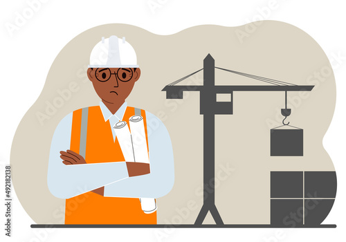 Sad engineer near the construction crane. Builder holding blueprints near construction machinery.