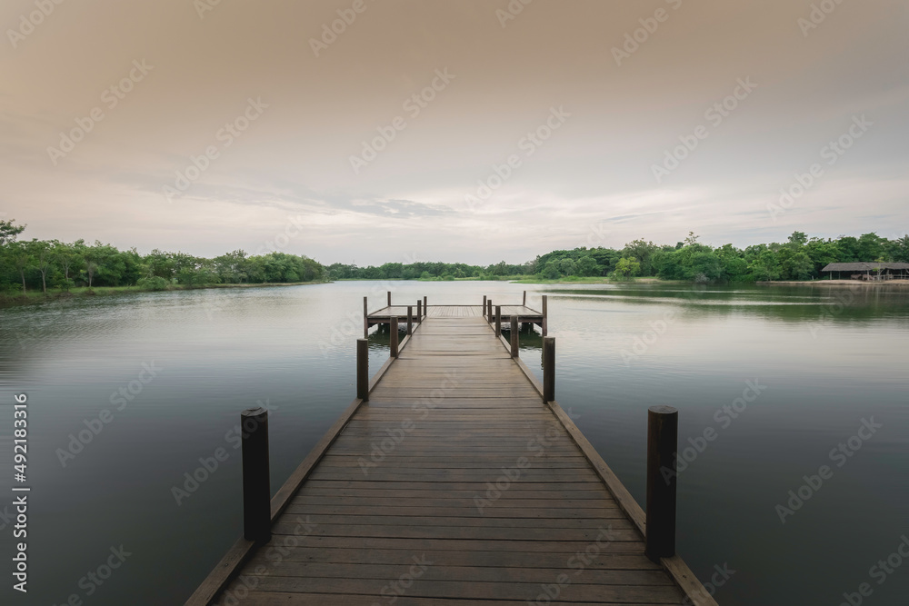 Fototapeta premium The wooden bridge stretches into the middle of the water. In the beautiful nature, evening
