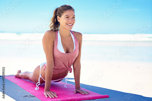 Yoga gives you more energy. Shot of a young woman doing yoga at the beach.