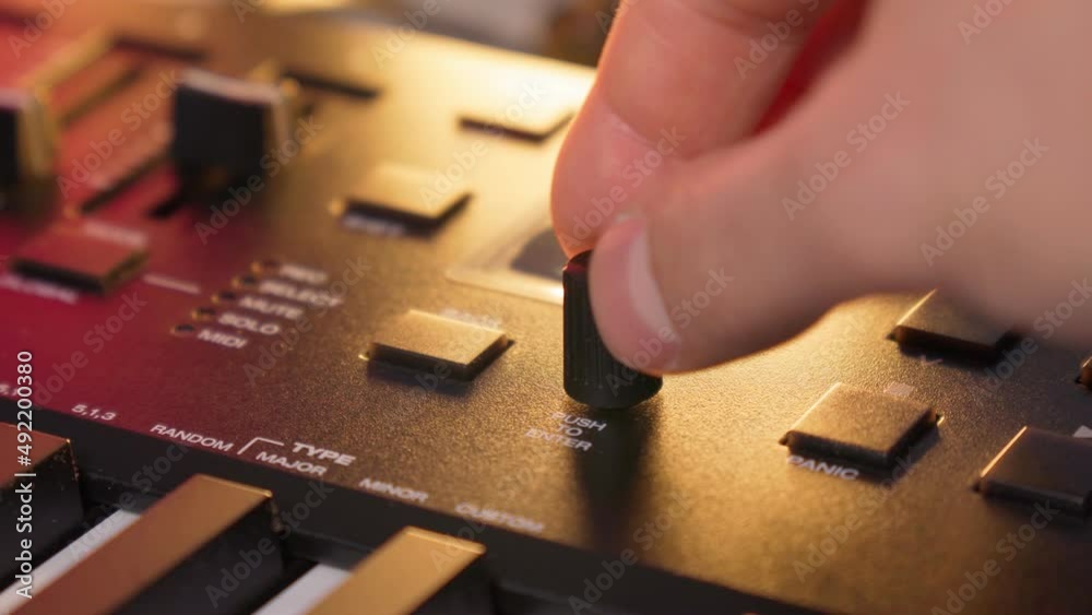 Midi keys on the table with neon lights. Closeup of male hands composing music using midi controller