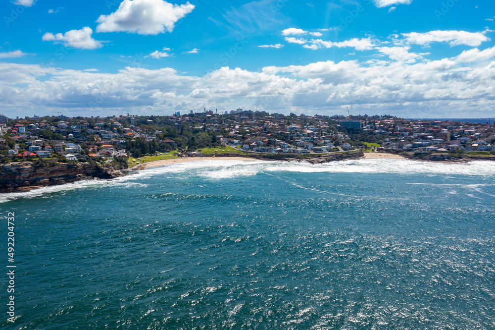 Aerial drone view of iconic Bronte Beach and Tamarama Beach coastline in Sydney, Australia during summer on a sunny day  