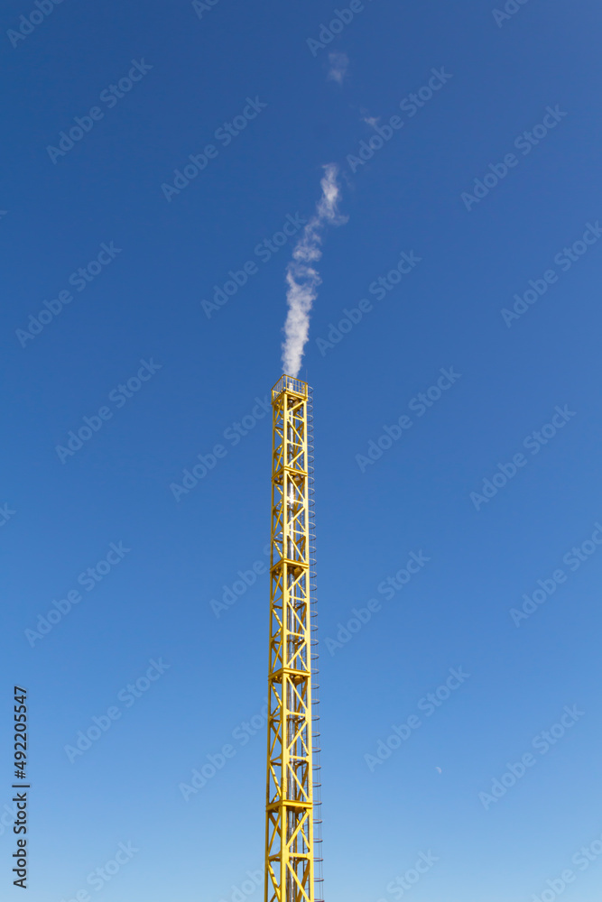 A new, yellow, working boiler room outside on a bright sunny day. Modern fuel and environmental pollution. A new, yellow, working boiler room outside on a bright sunny day. Modern fuel and environmental pollution.