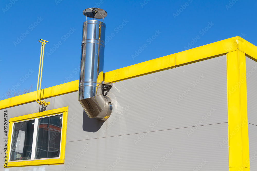A new, yellow, working boiler room outside on a bright sunny day. Modern fuel and environmental pollution.