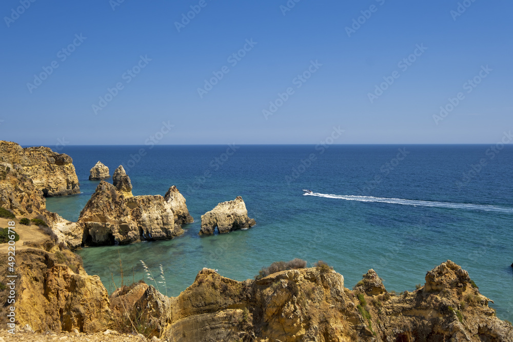 the idyllic Praia dos Tres Irmaos Beach surrounded by yellow cliffs and emerald sea in Portimao, Algarve, Portugal