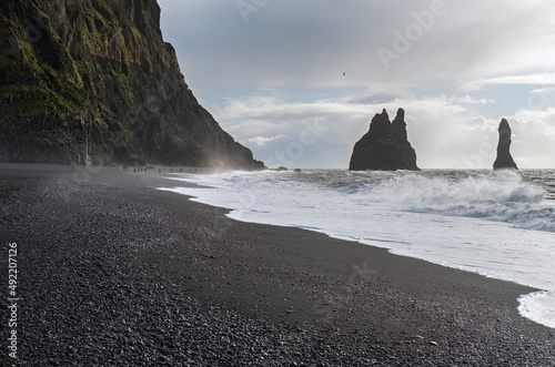 The famous Black Sand ocean Beach, mount Reynisfjall and Picturesque Basalt Columns, Vik, South Iceland. People unrecognizable.