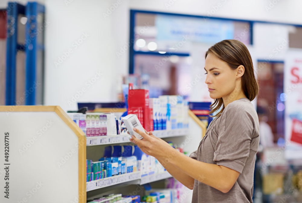 A young woman buying medicine in a pharmacy -The commercial designs displayed in this image represent a simulation of a real product and have been changed or altered enough by our team of retouching