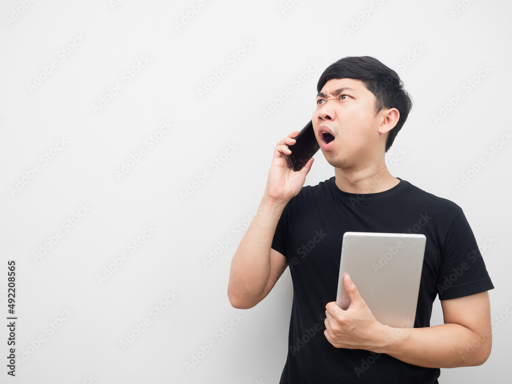 Man holding tablet with moblie phone feeling shocked looking at copy space