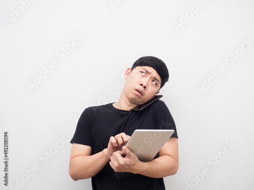 Busy man using tablet and talking mobile phone looking above copy space