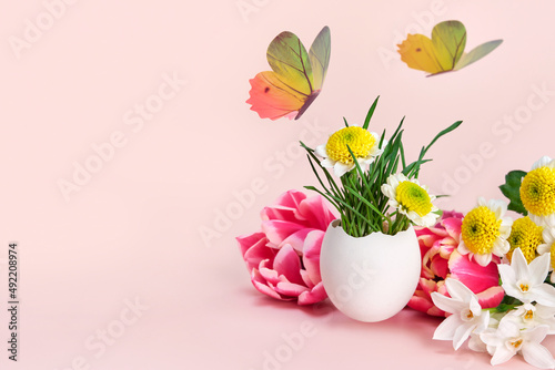 Easter creative composition. Spring flowers  Easter egg and butterflies on a pink background. Easter card