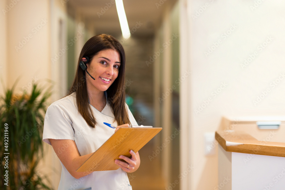 Smiling doctor writing notes on clipboard during call Smiling doctor writing notes on clipboard during call