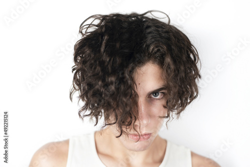 A teenager with long dark curly hair and a dramatic look, looks uncertainly at the camera, doubts what to do next, where to go to study. Sad teenager with dramatic face