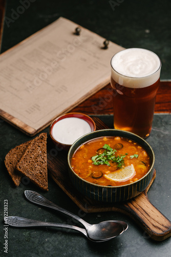 meat hodgepodge with sour cream, slices of black bread, light beer and menu. Serve in the pub