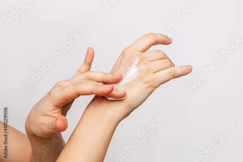 Close-up of woman's hands applying moisturizing cream on the skin isolated on a gray background. Skin care concept  © Марина Демешко