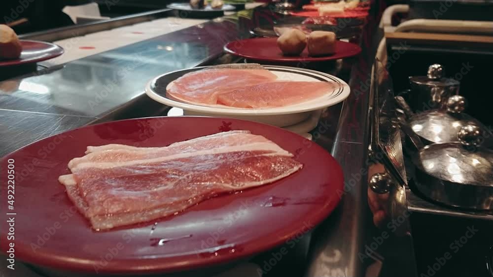 Row of japanese food buffet dishes on belt. Conveyor of Japanese food belt for hot pot or