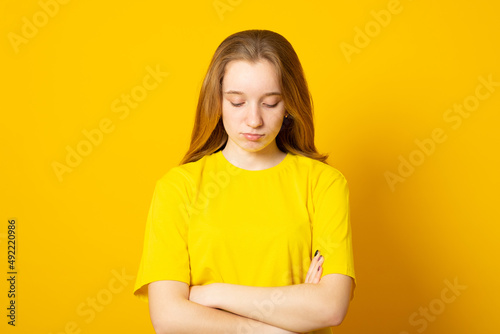 Sad teenager girl. Studio image of a cute young girl on yellow background..