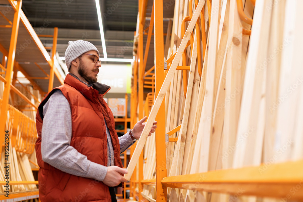 in a lumber store, a man chooses wooden blocks and boards in a lumber store, a man chooses wooden blocks and boards