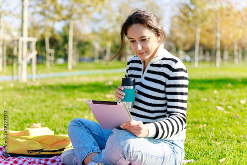 Young woman using tablet sitting in the park