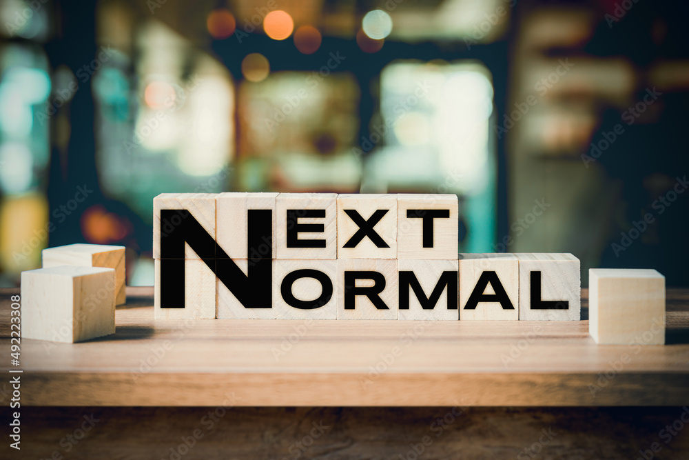 Next Normal word on wooden cube block on wood table background.