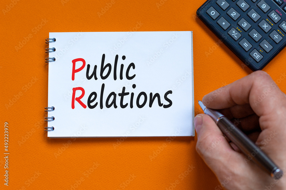 PR public relations symbol. Concept words PR public relations on white note. Businessman hand, calculator. Beautiful orange background. Copy space. Business and PR public relations concept. PR public relations symbol. Concept words PR public relations on white note. Businessman hand, calculator. Beautiful orange background. Copy space. Business and PR public relations concept.