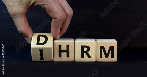 DHRM, domestic or international human resource management IHRM symbol. Words DHRM, IHRM on cubes on a beautiful grey background. Businessman hand. Business, DHRM IHRM concept. Copy space. photo