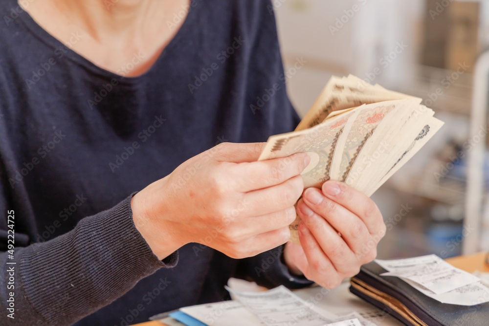 Obraz premium 家計のやりくりの為、お金を数える女性