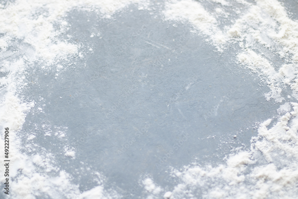 Obraz premium Flour spilling on color background of slate cutting board.