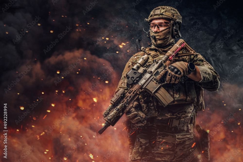 Obraz premium Special force soldier with firearm weapon against burning background