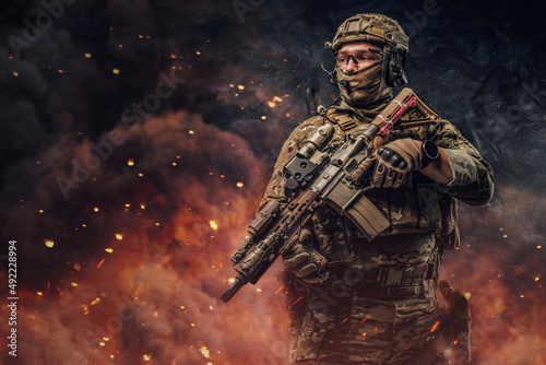 Special force soldier with firearm weapon against burning background © Fxquadro