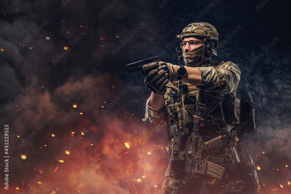 Special force soldier aiming pistol against explosions and fire Special force soldier aiming pistol against explosions and fire