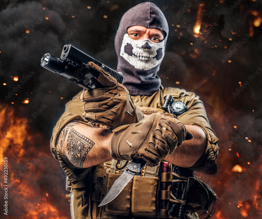 Naklejka premium Special force soldier with pistol and knife against burning background