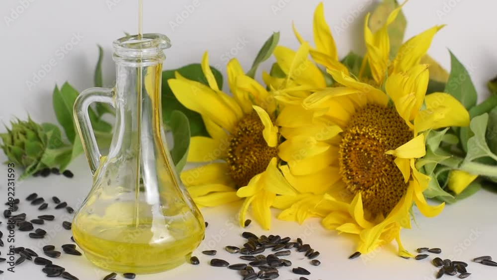 Sunflower oil is poured into a glass dish.Sunflower flower and seeds for the manufacture of oil Sunflower oil is poured into a glass dish.Sunflower flower and seeds for the manufacture of oil