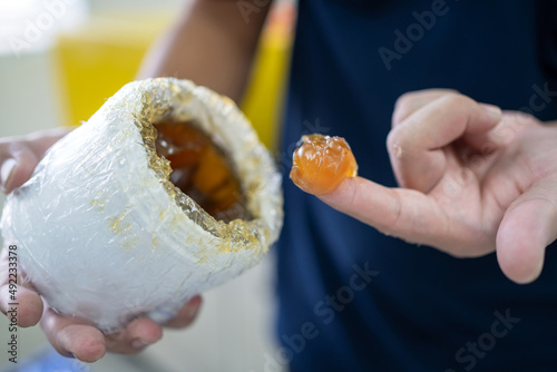 Worker use finger to scoop up lithium grease from white plastic can in the laboratory. Yellow transparance grease on the finger. Testing and manufacturing concept.