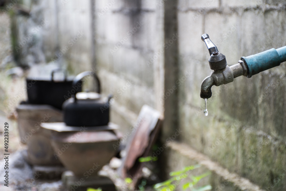 Naklejka premium Old faucet with water leaking drop to the ground