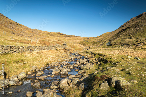 A sunny, winter HDR landscape image, looking west up Wrynose Pass with the infant River Duddon in the foreground, Cumbria, England photo