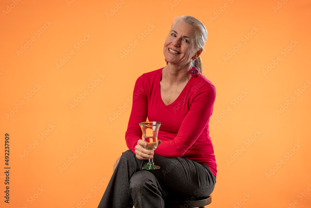 Portrait of mature woman holding cup smiling at camera isolated on orange background copy space. Portrait of mature woman holding cup smiling at camera isolated on orange background copy space.