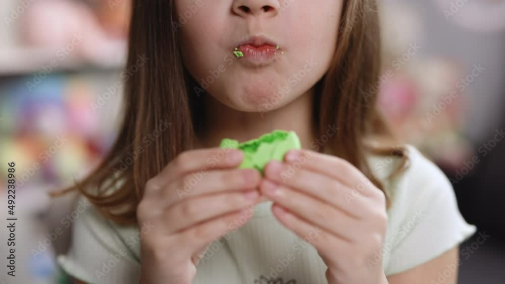 Close up of gorgeous school girl biting french macaroon, enjoying eating, confectionary desire and pleasure. Attractive brunette female girl on home background, licks her lips, eating macaron Close up of gorgeous school girl biting french macaroon, enjoying eating, confectionary desire and pleasure. Attractive brunette female girl on home background, licks her lips, eating macaron