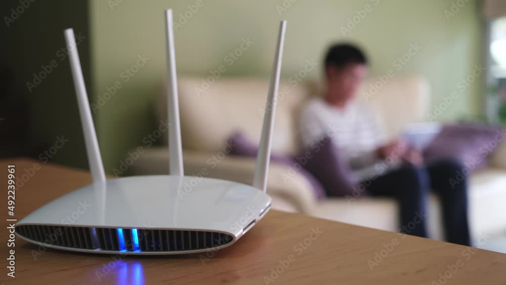 Selective focus at router. Internet router on working table with blurred man using tablet at the background. Fast and high speed internet connection from fiber line with LAN cable connection.