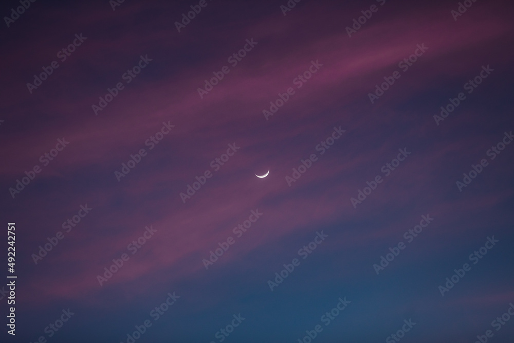 Luna creciente entre nubes y cielo narajan durante un atardecer espectacular. Luna creciente entre nubes y cielo narajan durante un atardecer espectacular.