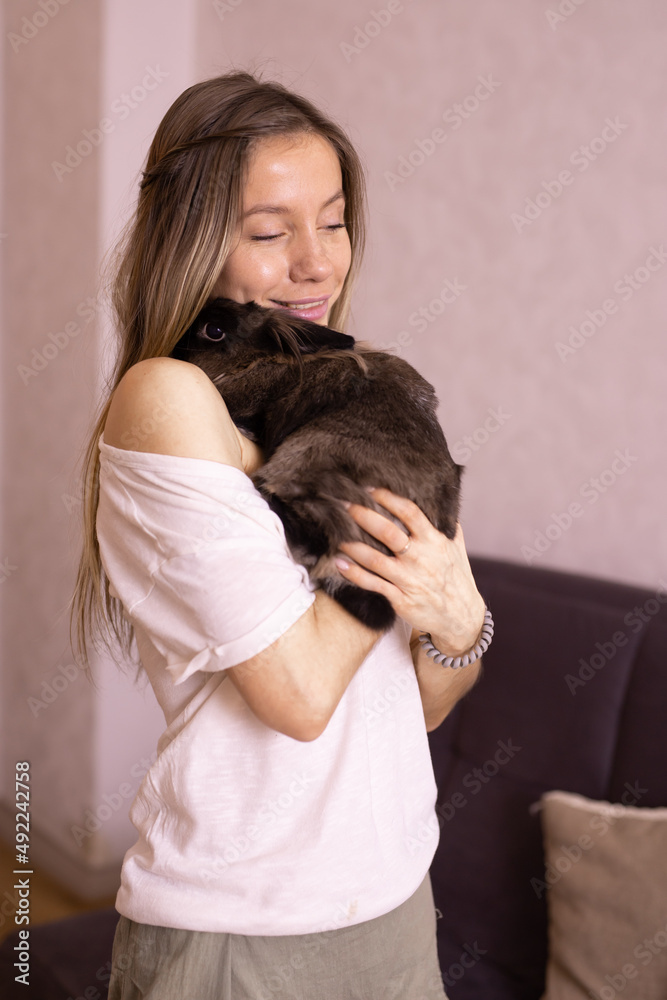 Young woman with adorable rabbit indoors, close up. Lovely pet and animal concept Young woman with adorable rabbit indoors, close up. Lovely pet and animal concept