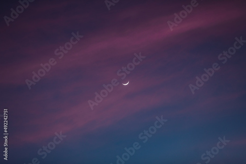 Luna creciente entre nubes y cielo narajan durante un atardecer espectacular. photo
