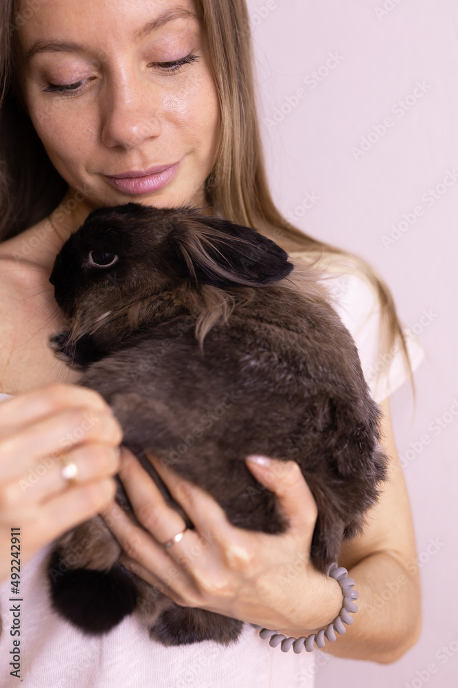 Close-up girl with adorable rabbit indoors, close up. Lovely pet and animal concept Close-up girl with adorable rabbit indoors, close up. Lovely pet and animal concept