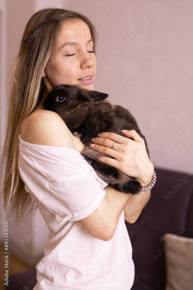 Young woman with adorable rabbit indoors, close up. Lovely pet and animal concept Young woman with adorable rabbit indoors, close up. Lovely pet and animal concept